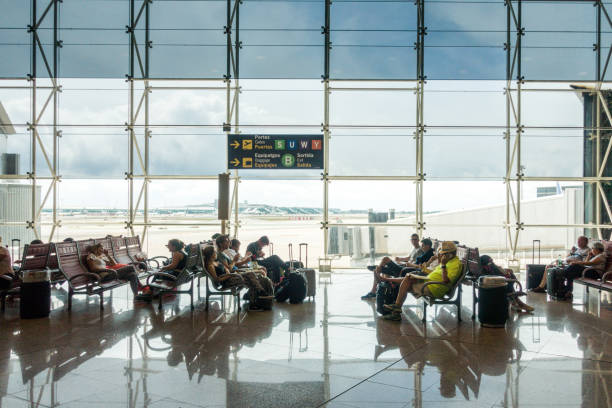 Sala de espera de la terminal del aeropuerto de Barcelona-El Prat con pasajeros esperando su vuelo tras llegar en taxi de largo recorrido